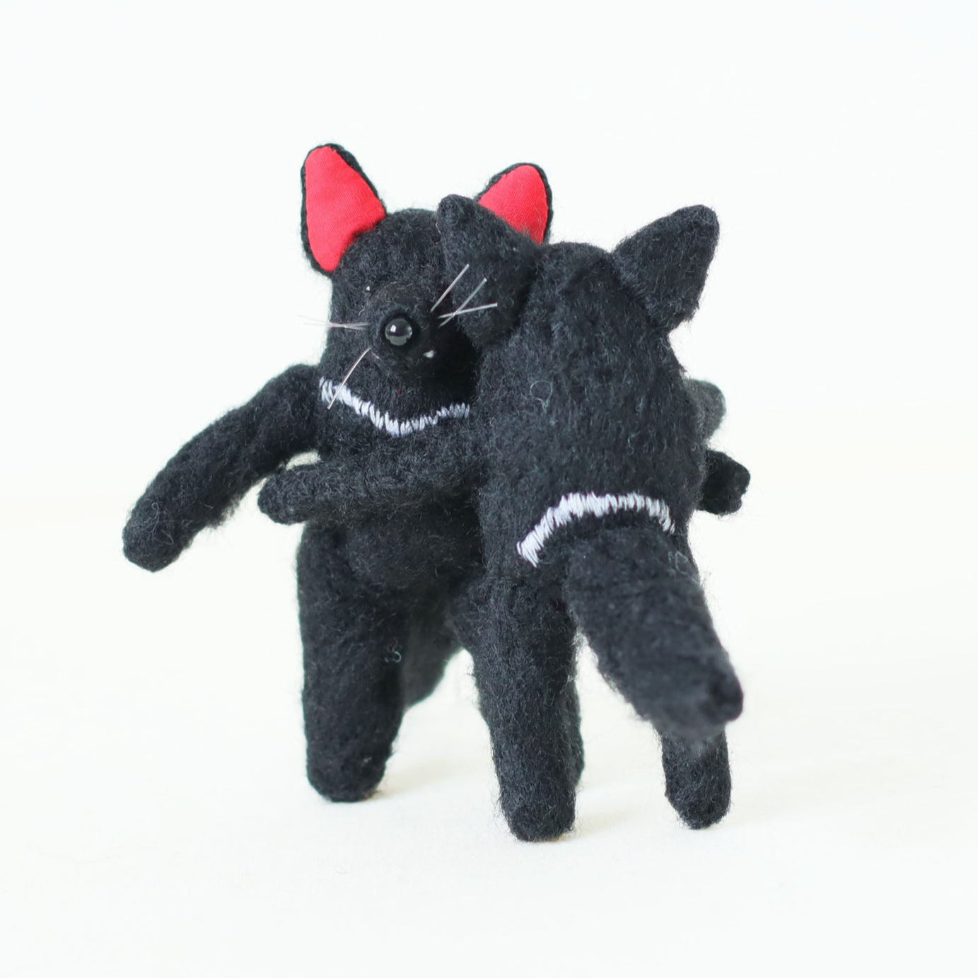 Pair of artisan Tasmanian devil plush dolls hugging — handmade collectible stuffed animals with black fur, red ears, and embroidered chest details.