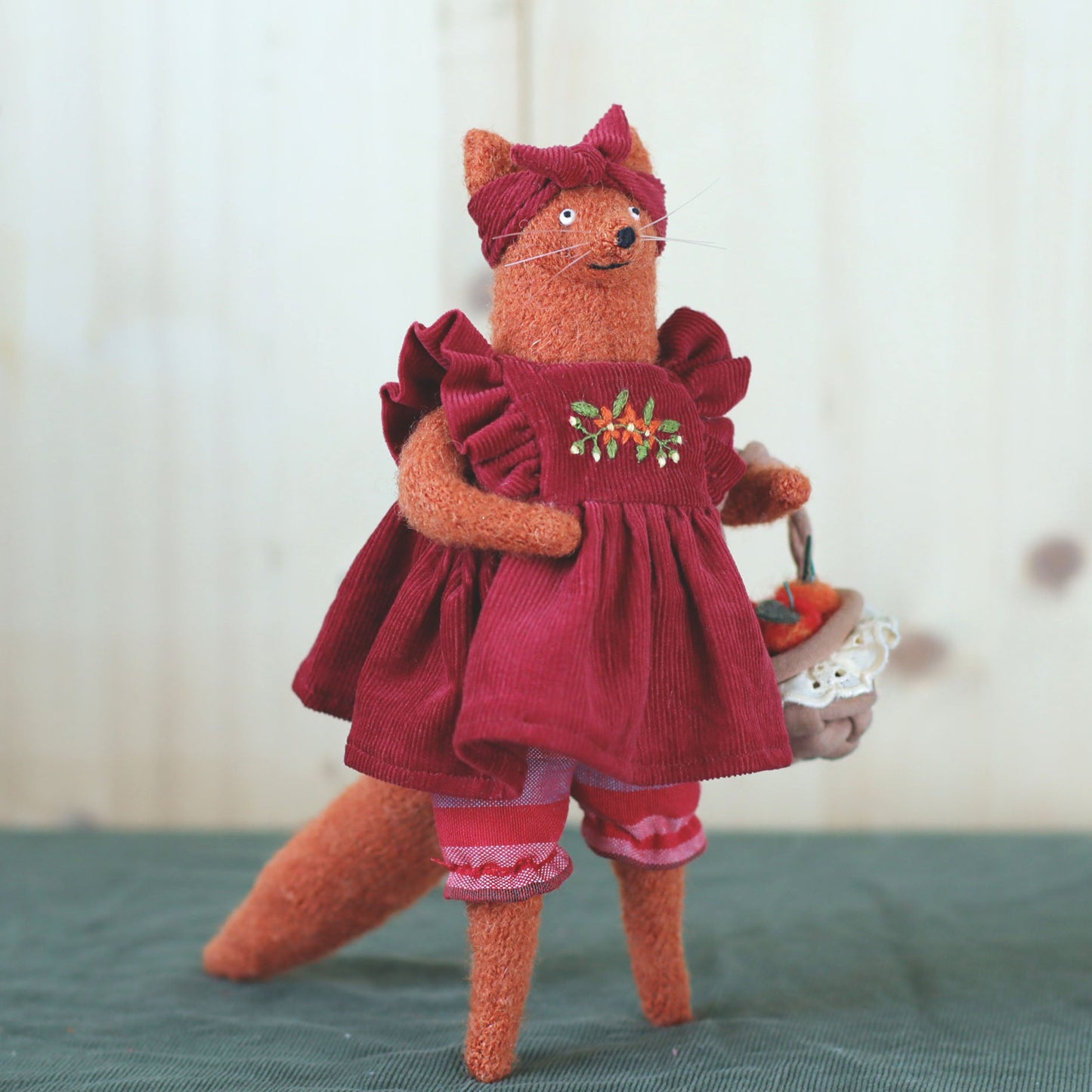Handmade fox doll in a red embroidered dress, holding a small basket of felted apples