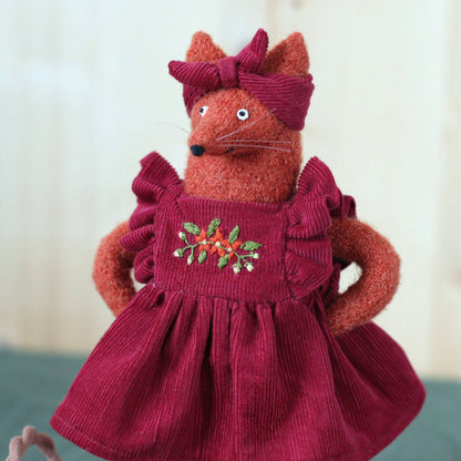 Handmade fox doll wearing a deep red corduroy dress with embroidered flowers and a matching headband
