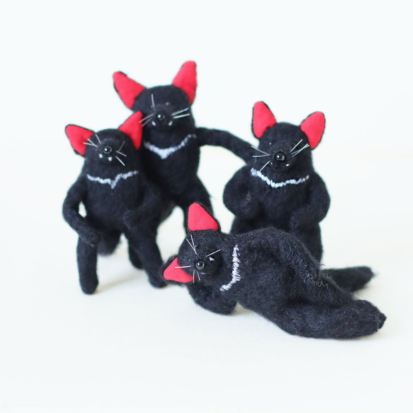 A group of handcrafted Tasmanian devil plush toys with soft black fur, bright red ears, and white chest stripes, posing together.