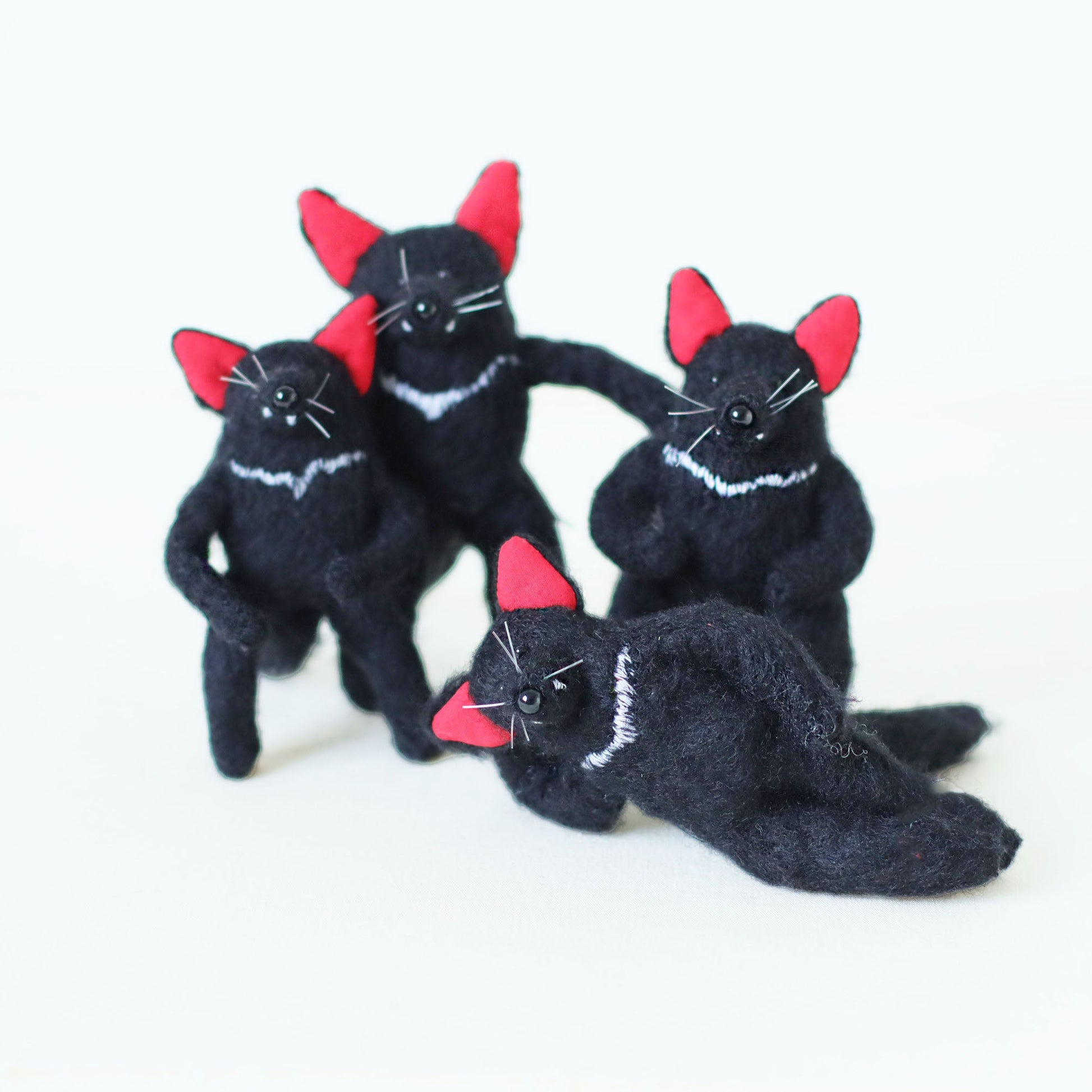 A group of handcrafted Tasmanian devil plush toys with soft black fur, bright red ears, and white chest stripes, posing together.