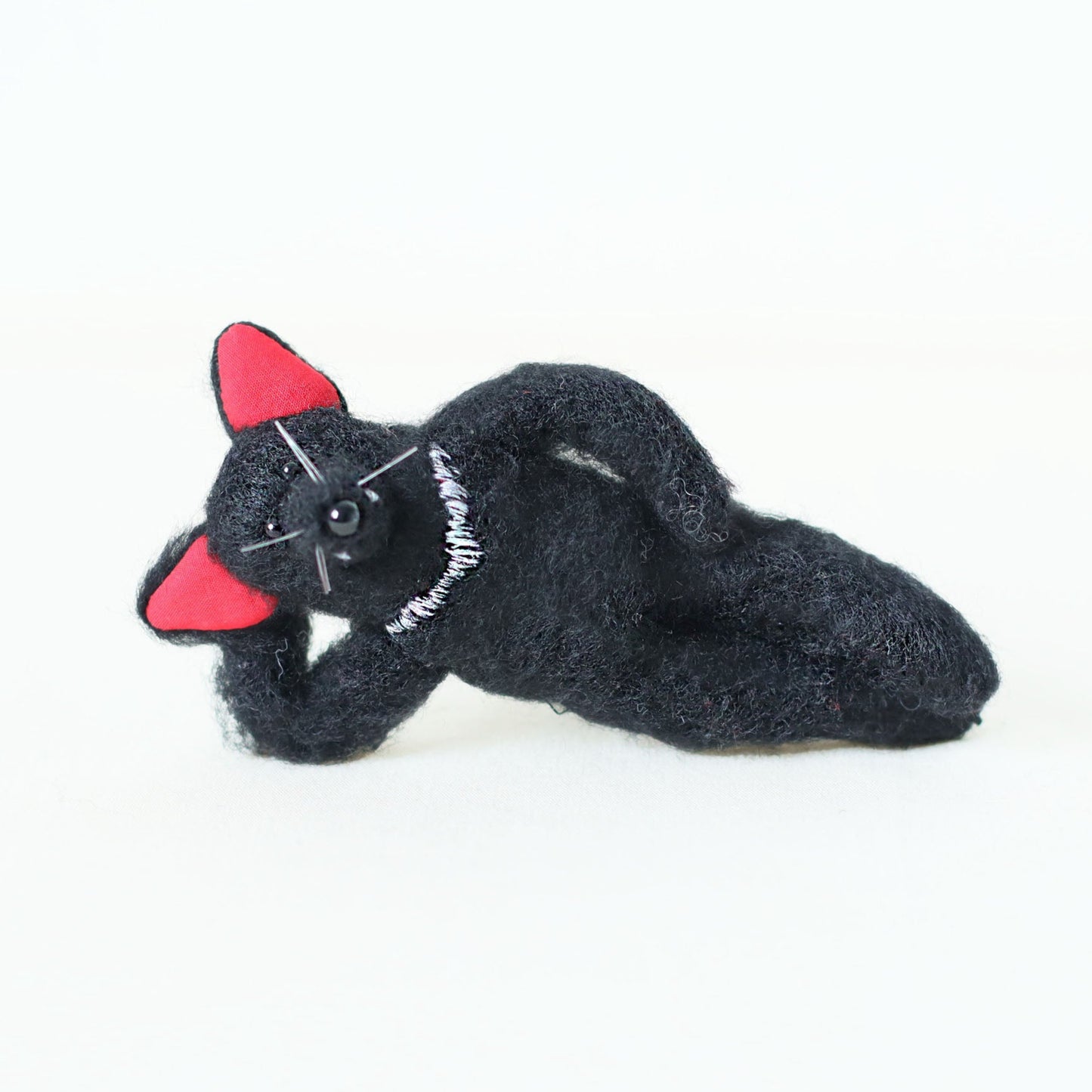 Handmade Tasmanian devil plush doll, lying on its side in a relaxed pose — hand-sewn stuffed animal, artisan soft toy, collectible plush.