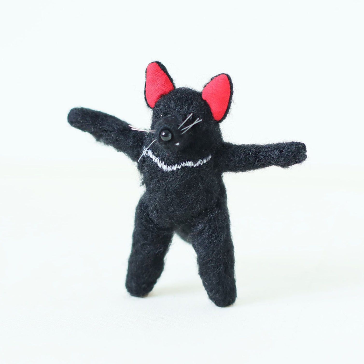Artisan Tasmanian devil plush doll standing upright with arms stretched wide — handmade collectible stuffed animal with black fur, red ears, and embroidered chest detail.