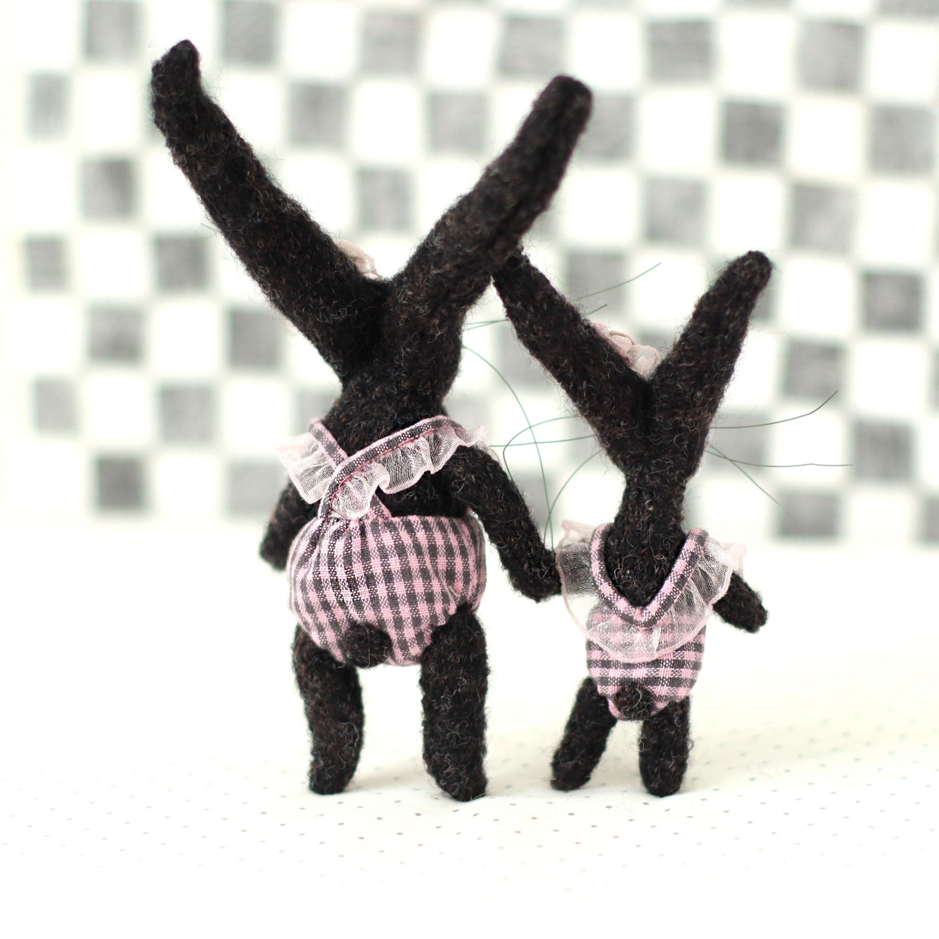 Handmade dark brown wool bunny collectible plush set — miniature rabbits in pink checked outfits, shown from the back, standing together with long upright ears
