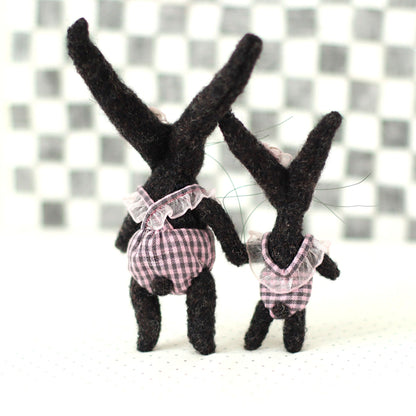 Handmade dark brown wool bunny collectible plush set — miniature rabbits in pink checked outfits, shown from the back, standing together with long upright ears