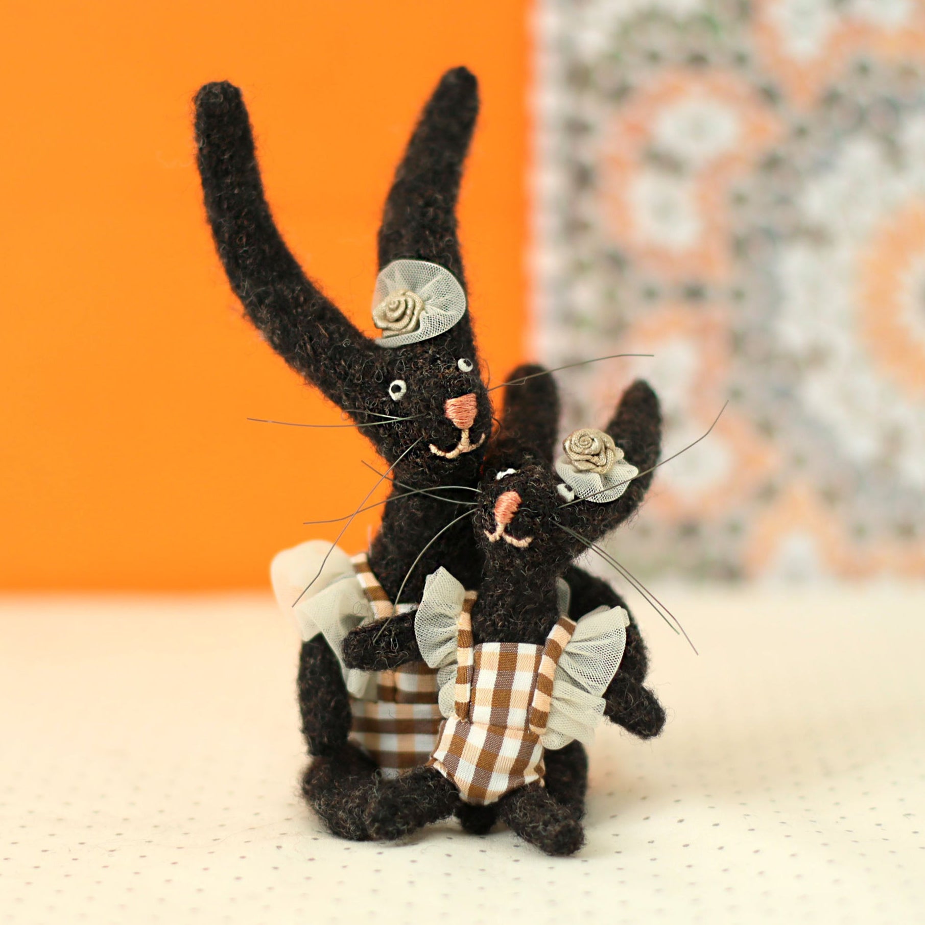 Handmade black bunny collectible plush set — mother and daughter rabbits in gingham outfits with tiny floral headpieces, sitting and cuddling