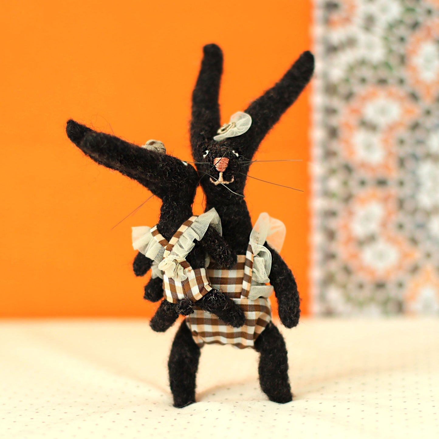 Handmade black bunny collectible plush set — mother and child rabbits in plaid outfits with ruffled straps, the mother holding and lifting the little bunny in a playful pose.