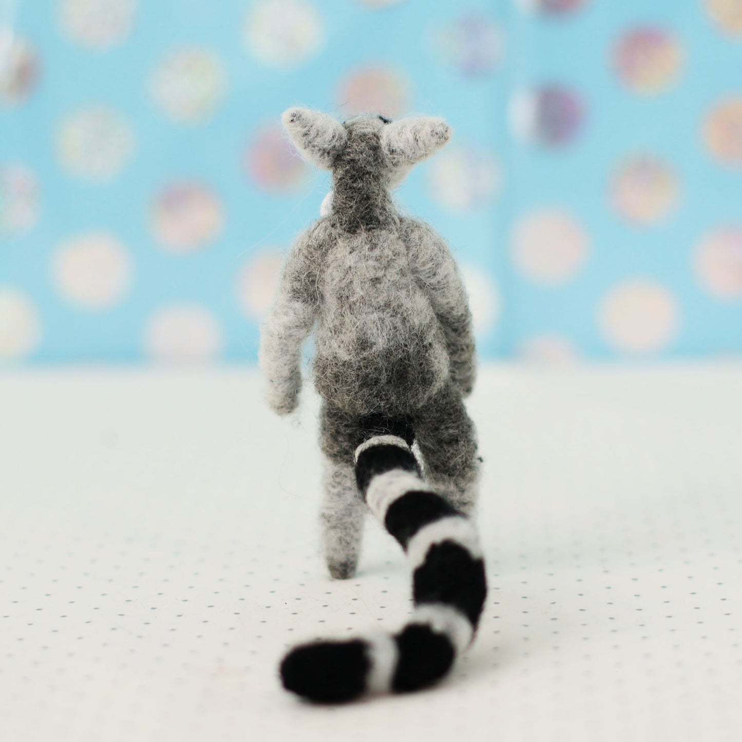 Handmade ring-tailed lemur collectible plush — back view showing striped tail and wool texture, miniature soft sculpture.