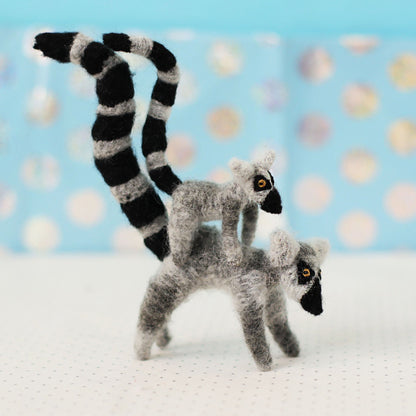 Two toy lemurs with black and white striped tails on a light blue background with polka dots.